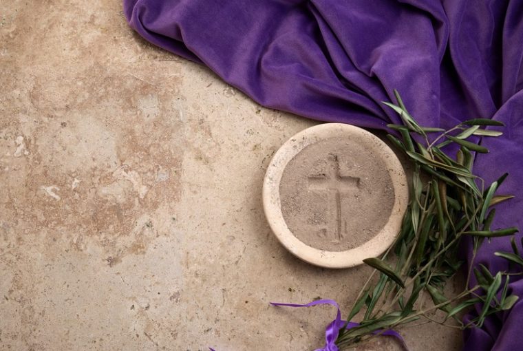 sfondo di pietra su cui sono posati mantello viola, palme, piatto di pietra con cenere in cui è stata fatta una croce; Mercoledì delle Ceneri