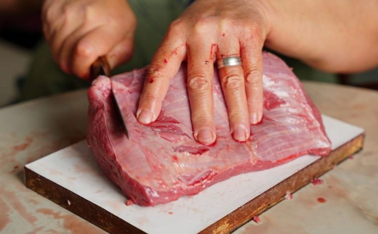 La carne di cavallo divide ancora tra tabù e regole diverse: Immagine dettagliata di mani che, con un coltello, tagliano un…