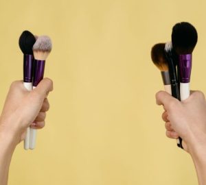Contouring per principianti: tecniche semplici per definire il viso: Due mani che tengono vari pennelli per trucco su uno…